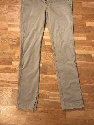 Beige chinos från NN07 - Snygga beige chinos med fin passform och klassisk design. Byxorna har diskreta fickor fram och bak, samt bälteshällor i midjan. Tillverkade i ett mjukt och bekvämt bomullsmaterial som passar perfekt till en avslappnad stil.