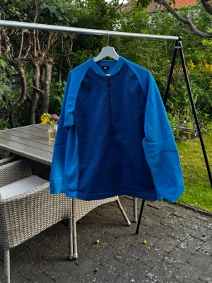Träningströja - Snygg blå ziptröja med två olika nyanser av blått. Tröjan har hel dragkedja framtill, ribbade muddar och en cool struktur på ärmarna. Perfekt för dig som gillar en sportig och avslappnad stil. Har aldrig använt för träning, bara ute 1 gång