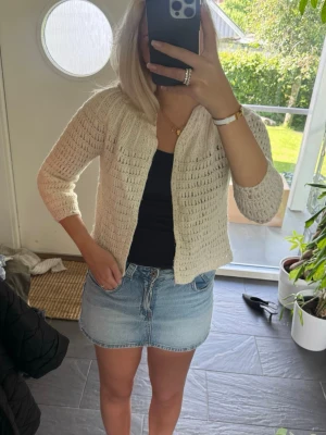 Beige virkad kofta med trekvartsärm - Söt beige virkad kofta med trekvartsärm och öppen framtill. Koftan har ett luftigt mönster och är perfekt att slänga över ett linne eller t-shirt. Passar till både jeans och kjol för en avslappnad look.