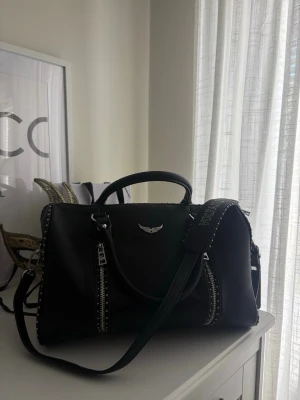 Zadig Voltaire - M Sunny Bag - Säljer en svart M Sunny Studs Bag i fint skick. Väskan har dubbla handtag samt avtagbar/justerbar axelrem. Dragkedjorna fungerar som de ska och väskan är rymlig med ett stilrent svart tygfoder invändigt. Dusty Bag medföljer!  Om äkthet: Jag köpte väskan i andra hand. Hen jag köpte av hade äkhetsbevis och kvitto. Skriv privat för kvitto 🫶🏼.