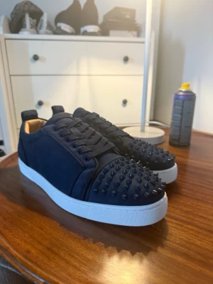Christian Louboutin str43 - Christian Louboutin Louis Junior Spikes – Marinblå – Strl 43  Säljer ett par exklusiva Christian Louboutin Louis Junior Spikes i marinblå mocka med vita sulor och de klassiska röda undersulorna.  * Storlek: 43 * Färg: Marinblå * Material: Mocka * Skick: Använda endast en gång, i mycket fint skick.  Pris: 1 799 kr  Säljs eftersom de inte kommer till användning.  Låda samnt tillbehör medföljer 