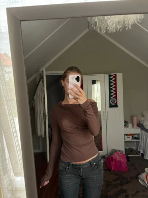 Brun långärmad topp med offshoulder - Säljer en brun långärmad topp med offshoulder-design. Toppen har en tight passform och är tillverkad i ett mjukt, stretchigt material som sitter snyggt på kroppen. Perfekt för dig som gillar en enkel men trendig stil.