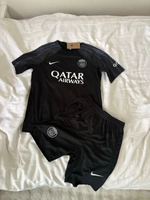 Svart PSG fotbollskit från Nike - Psg fotbollsset i storlek S. Shortsen har fickor med dragkedjor. Helt nya och oanvända, perfekt till sommaren. Hör gärna av vid frågor!
