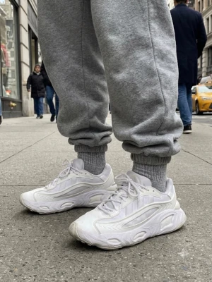 Vita Adidas Oznova sneakers - Säljer ett par vita Adidas Oznova sneakers med chunky sula och futuristisk design. Skorna har mesh och syntetmaterial i ovandelen, samt vita snören och detaljerade paneler. Perfekta för dig som gillar streetwear och vill sticka ut.
