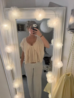 Beige kortärmad blus från Gina Tricot - Luftig och flowy beige blus från Gina Tricot i storlek XS aldrig använd . Blusen har djup v-ringning, korta ärmar och ett rynkat, avslappnat fall. Perfekt till sommaren och lätt att styla med både jeans och kjol.