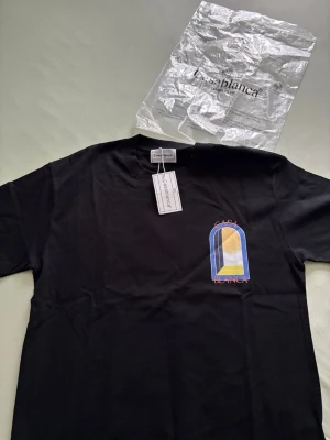 Svart Casablanca t-shirt med tryck - Casablanca t-shirt i svart med färgstarkt grafiskt tryck fram och stort tryck på ryggen. T-shirten har rund hals och korta ärmar. Materialet är mjuk bomull och passformen är normal. Perfekt för dig som vill ha en stilren men ändå unik look.