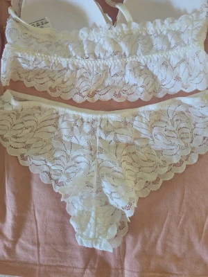 Vitt spetsunderklädesset med bralette - Säljer ett superfint vitt underklädesset i spets med bralette och matchande trosor. Setet har ett romantiskt bladmönster och mjuk, stretchig spets som känns bekväm mot huden. Perfekt för dig som gillar en feminin och trendig look.