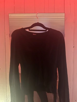 Svart långärmad tröja Gina Tricot - En enkel svart långärmad tröja från Gina Tricot med rund halsringning. Tröjan har en klassisk passform och är tillverkad i ett mjukt, stretchigt material som passar perfekt till alla typer av outfits.