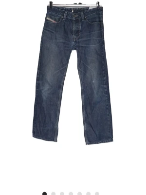 Mörkblå Diesel Larkee - Säljer ett par mörkblå jeans från Diesel med rak passform och klassisk femficksdesign. Jeansen har diskreta slitningar och en liten logga på myntfickan. Tillverkade i slitstark denim med snygg tvättad look.