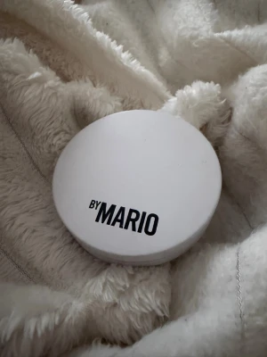 By Mario bronzer i kompaktformat - Säljer en bronzer från By Mario i en rund, vit kompakt med spegel. Bronzern har en varm brun nyans och är i puderform, perfekt för att ge ansiktet en solkysst look. Smidig att ha med i väskan och enkel att applicera.