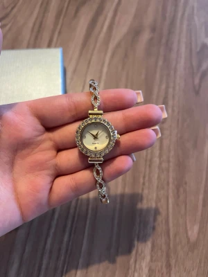 Klocka - Säljer då den inte kommer till användning. Den är justerbar. Den har guld detaljer samt diamanter.