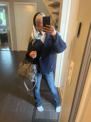 Mörkblå dubbelknäppt rock - Snygg mörkblå rock med dubbelknäppning och bred krage. Modellen är något boxig och har en klassisk marin känsla. Perfekt för dig som gillar stilrena och tidlösa plagg. Rocken har två framfickor och stora knappar.