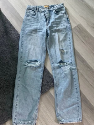 Ljusblå ripped straight jeans - Säljer ett par ljusblå jeans straight och slitna detaljer på båda benen. Jeansen har klassisk femficksdesign, normal midja och är tillverkade i denim. Perfekta för en avslappnad och trendig look. Högd/medel midja!❤️