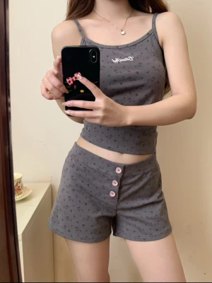 Grå pyjamas-set med linne och shorts - Säljer ett grått pyjamas-set från Disney med linne och shorts. Setet har små tryckta motiv, rosa knappar på shortsen och smala axelband. Perfekt för mysiga kvällar hemma.