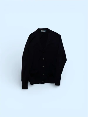 Svart kofta från Ralph Lauren - Klassisk svart kofta från Ralph Lauren med v-ringning och knäppning framtill. Tillverkad i mjukt material och har två fickor framtill. Perfekt för lager på lager och enkel att matcha med olika outfits.