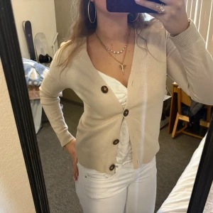 Beige kofta från Massimo dutti - Snygg beige kofta med v-ringning och stora bruna knappar framtill från Massimo dutti. Älskar denna så mkt. Perfekt till ett par vita jeans!❤️