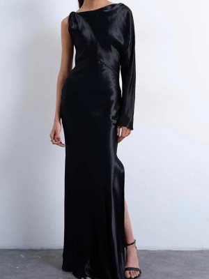 Svart asymmetrisk satin balklänning - Elegant svart långklänning i glansigt satinmaterial med oneshoulder-design och lång ärm på ena sidan. Klänningen har en smal passform och en slits på sidan för extra stilpoäng. Perfekt för dig som vill sticka ut med en unik och sofistikerad look. Aldrig använd och prislapp kvae