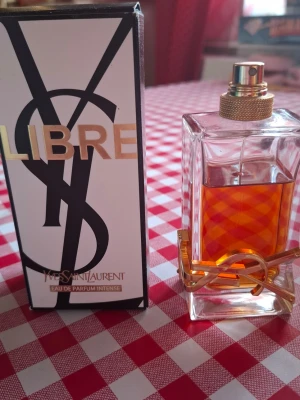 Yves Saint Laurent Libre Intense EdP - Yves Saint Laurent Libre Eau de Parfum Intense är en lyxig parfym i en rektangulär glasflaska med guldiga detaljer och YSL-logga. Doften har en djup bärnstensfärg och flaskan har en elegant guldfärgad spraykork. Förpackningen är svartvit med guldtext. Tyvärr är locket borta. Se bild hur mycket det är kvar.