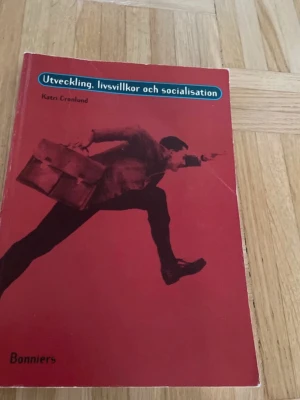 Utveckling, livsvillkor och socialisation - Kursbok med röd mjukpärm, skriven av Katri Cronlund. Boken tar upp frågor om barns utveckling, rättigheter, lekens betydelse, tonårstid och sociala skillnader. Passar för gymnasiekurser inom psykologi och samhällskunskap.