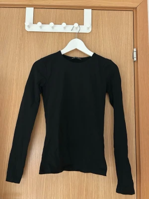 Svart långärmad topp från Zara - En svart långärmad topp från Zara med rund halsringning. Tight passform som sitter snyggt på kroppen. 