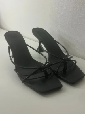 Svarta klackskor med öppen tå - Säljer dessa skit snygga klackar med öppen tå!! Så fina på sommaren. Skorna är oanvända men har varit i en resväska så därav är exempelvis texten i lite utsuddad. Från Pretty little thing och storlek 38, sanna till storleken! Väldigt stabila och enkla att gå i, inte för höga men ändå stilrena och snygga☺️minns inte nypris men säljer för 199 kr! 