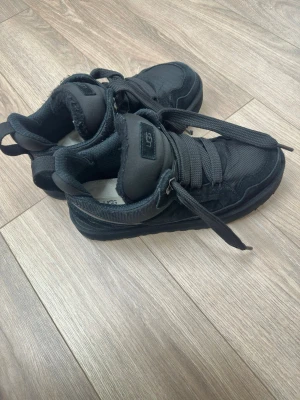 UGG Lowmel Trainer ”Black” 44 - Säljer ett par UGG Lowmel Trainer i svart, storlek 44. Skorna är lite använda och i väldigt bra skick.  De hade tidigare ett litet hål, men de skickades in till UGG för reparation, så detta är åtgärdat.   Skorna är sköna, stabila och passar perfekt till vardags.  Pris kan diskuteras vid snabb affär. Hör av dig om du vill ha fler bilder eller frågor.