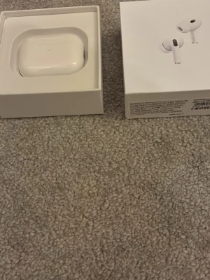 Apple AirPods Pro med laddningsetui - Säljer ett par vita Apple AirPods Pro med trådlöst laddningsetui. Hörlurarna är in-ear och levereras i originalförpackning med laddningskabel och extra öronproppar. Snygg och stilren design i blank plast, perfekt för dig som vill ha grymt ljud och smidig anslutning till din iPhone.