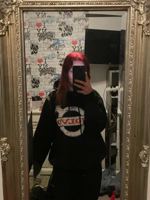 Svart Volvo hoodie med tryck - Säljer en svart hoodie med stor vit och röd Volvo-logga på bröstet. Hoodien har huva och en avslappnad passform, perfekt för dig som gillar streetwear och vill sticka ut med en klassisk bilstil.