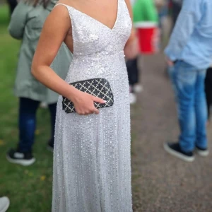 Vit glittrig långklänning med paljetter - Säljer min balklänning, endast använd en gång. Vit med paljetter, den går rakt ner med öppen rygg. Storlek xs/s. Jag är 165cm