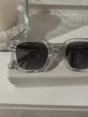 Transparenta solglasögon från chimi  - Snygga solglasögon från chimi med transparent, fyrkantig båge i syntet och mörka glas. Modern och stilren design som ger en cool vibe till din look. Perfekta för soliga dagar och lätta att matcha med olika outfits. Knappt använda.