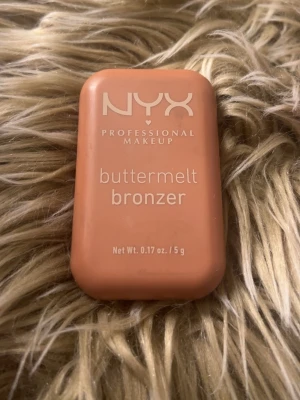 NYX buttermelt bronzer  - NYX Professional Makeup buttermelt bronzer i en varm, gyllenbrun nyans som är Butta D Down!!. Kommer i en kompakt, rektangulär dosa med lock och har ett snyggt mönster i pudret. Perfekt för att skapa en solkysst look och enkel att ta med i väskan.