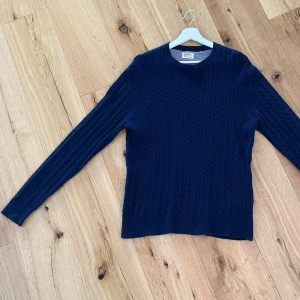 Mörkblå kabelstickad tröja Crocker - Snygg mörkblå kabelstickad tröja från Crocker med rund halsringning. Klassisk design med strukturstickat mönster som passar perfekt till jeans eller chinos. Tillverkad i mjukt material för en bekväm känsla.