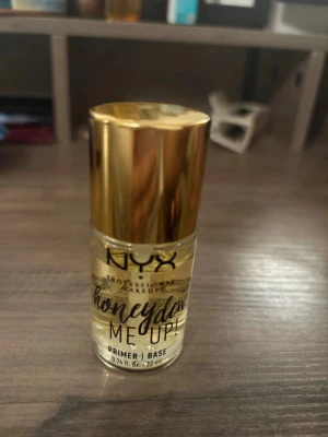 NYX Honey Dew Me Up Primer - NYX Honey Dew Me Up Primer är en genomskinlig primer med guldfärgade detaljer och guldlock. Den har en gel-liknande formula och kommer i en liten glasflaska. Perfekt för att skapa en fräsch och glowig bas innan sminket. För fler bilder/information skriv gärna, priset kan justeras 🤗❤️
