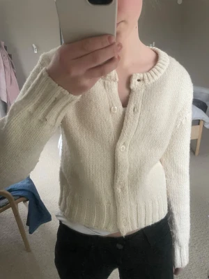 Krämvit kofta från Zara - Mysig krämvit stickad kofta från Zara med rund halsringning och knäppning framtill. Koftan har ribbstickade muddar vid ärmslut och nederkant, och är tillverkad i ett mjukt garn som känns skönt mot huden. Perfekt att slänga på sig över en t-shirt. Koftan är även lite nopprig men syns i från distan, samt går att använda noppringmaskin för att få bort.💕💕