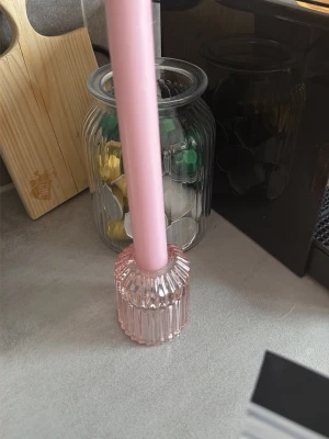Rosa ljusstake i glas - Säljer en stilren ljusstake i rosa glas med räfflad design. Ljusstaken har en rund form och passar perfekt för att skapa mysig stämning i hemmet. 