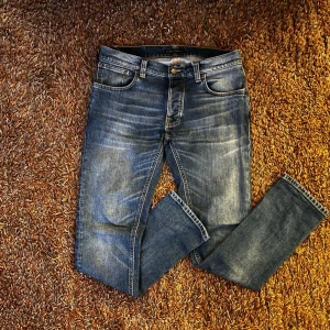 Blå jeans från Nudie Jeans w32 l32 - Säljer ett par klassiska blå jeans från Nudie Jeans med snygg tvätt (storlek W32 L32). ‼️ Riktigt bra skick på dessa ‼️ Modellen har fem fickor, raka ben och kontrastsömmar. Perfekta för dig som gillar en avslappnad men ändå stilren look.