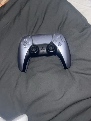 Svart PlayStation 5 DualSense kontroll - Snygg svart PlayStation 5 DualSense handkontroll från Sony. Ergonomisk design med två analoga spakar, touchpad och klassiska PlayStation-knappar. Tillverkad i matt plast med detaljer i svart och grått. Perfekt för gaming på PS5. Nästan helt ny fungerar helt felfritt 