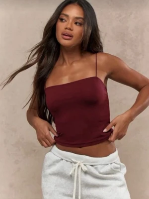 Vinrött linne med tunna axelband - Säljer ett vinrött linne med tunna axelband och rak urringning. Toppen är figurnära och har en enkel, stilren design som passar perfekt till jeans eller kjol. Materialet känns mjukt och stretchigt, vilket gör den bekväm att bära hela dagen.