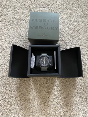 Omega x Swatch Mission to Mercury - Säljer en Omega x Swatch Speedmaster MoonSwatch Mission to Mercury. Klockan har en mörkgrå boett och svart urtavla med vita detaljer. Kommer i originalbox med tillhörande manualer. Snygg och unik klocka för dig som gillar cool design.