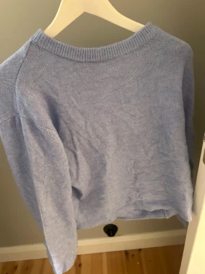 Ljusblå stickad tröja - En enkel och stilren ljusblå stickad tröja med rund halsringning och långa ärmar. Tröjan har en mjuk och avslappnad passform, perfekt att matcha med jeans eller kjol. Materialet känns mjukt och bekvämt mot huden.