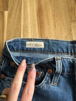 Levi's Premium blå jeans man - Säljer ett par klassiska blå Levi's Premium jeans i denim med fem fickor och kopparfärgade nitar. Jeansen har normal midja och raka ben, perfekt för en avslappnad och tidlös look. Materialet är slitstarkt bomullsdenim.