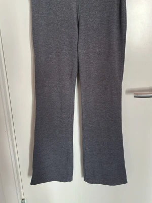 Grå mjukisbyxor med utsvängda ben - Säljer ett par grå mjukisbyxor med utsvängda ben. Byxorna har en enkel och clean look utan synliga loggor eller detaljer. Tillverkade i mjukt och stretchigt material som känns skönt mot huden. Perfekta för chill dagar eller när du vill vara bekväm.