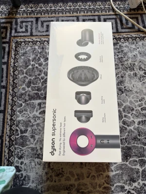 Dyson Supersonic hårfön - Säljer en Dyson Supersonic hårfön i svart och rosa med flera stylingmunstycken. Ergonomisk design och avancerad teknik för snabb torkning utan extrem värme. Perfekt för olika hårtyper och enkel att använda. Levereras i originalförpackning.