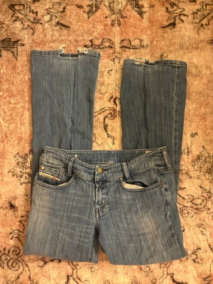 Blå jeans Diesel Louvely W30 L30 - Säljer ett par klassiska blå jeans från Diesel, modell Louvely. Jeansen har en rak passform, fem fickor och slitna detaljer vid bensluten. Tillverkade i stretchigt denim för extra komfort. Perfekta för en avslappnad och trendig look.