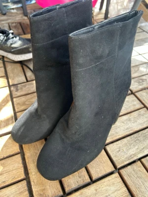 Svarta mockastövletter med klack - Snygga svarta stövletter i mockaimitation med rund tå och hög, bred klack. Dragkedja på insidan för enkel på- och avtagning. Stilren design som passar till många olika outfits.