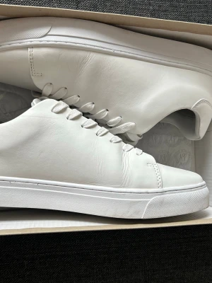 Vita minimalistiska sneakers i läder - Säljer ett par helvita sneakers från Pace i mjukt läder. Skorna har en clean och stilren design med vita snören och sula. Perfekta för dig som gillar en enkel men snygg look. Klassisk low-top modell som passar till det mesta.