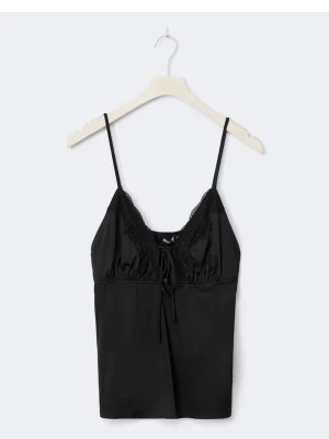 Svart spetslinne med tunna band - Snyggt svart linne i satinliknande material med tunna axelband och spetsdetaljer vid bysten. Linnet har en liten rosett framtill och en mjuk, följsam passform. Perfekt för dig som gillar en stilren och feminin look.