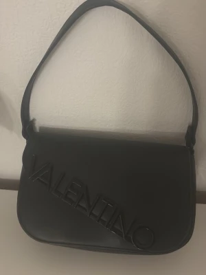 Svart axelremsväska från Valentino - Stilren svart handväska från Valentino. Använd fåtal gånger och i mycket bra kvalité! Väskan säljs för 840 kr , hör av er vid funderingar 🌸