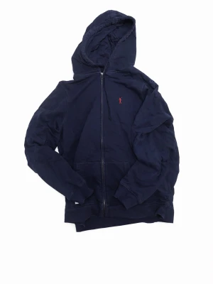 Mörkblå hoodie från Polo Ralph Lauren - Mörkblå hoodie med dragkedja från Polo Ralph Lauren. Klassisk design med huva och fickor framtill. Liten röd logga broderad på bröstet. Tillverkad i mjukt bomullsmaterial som känns skönt mot huden. Perfekt för en avslappnad och stilren look.