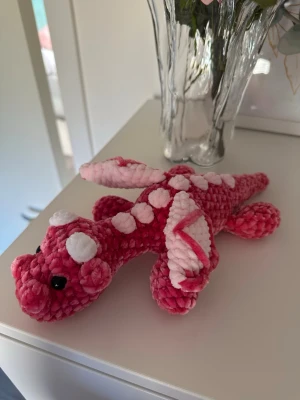 Virkad rosa drake - Virkad rosa drake med ljusrosa detaljer. Ca 27 cm lång. Den har säkerhetsögon som inte är lämpliga för barn under 3 år💗